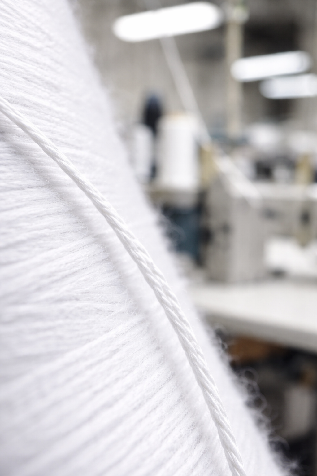 Detalle macro de hilo blanco industrial mostrando textura y doble cabo 30/2 40/2